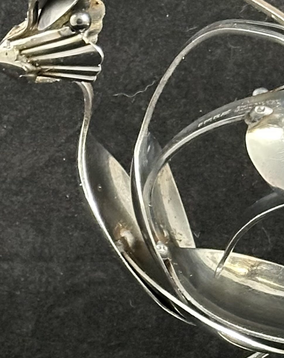 Bluejay-like bird made of reclaimed cutlery, perched on a bent spoon